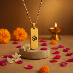 24K gold OM necklace on a circular stand with flower petals and a candle in the background